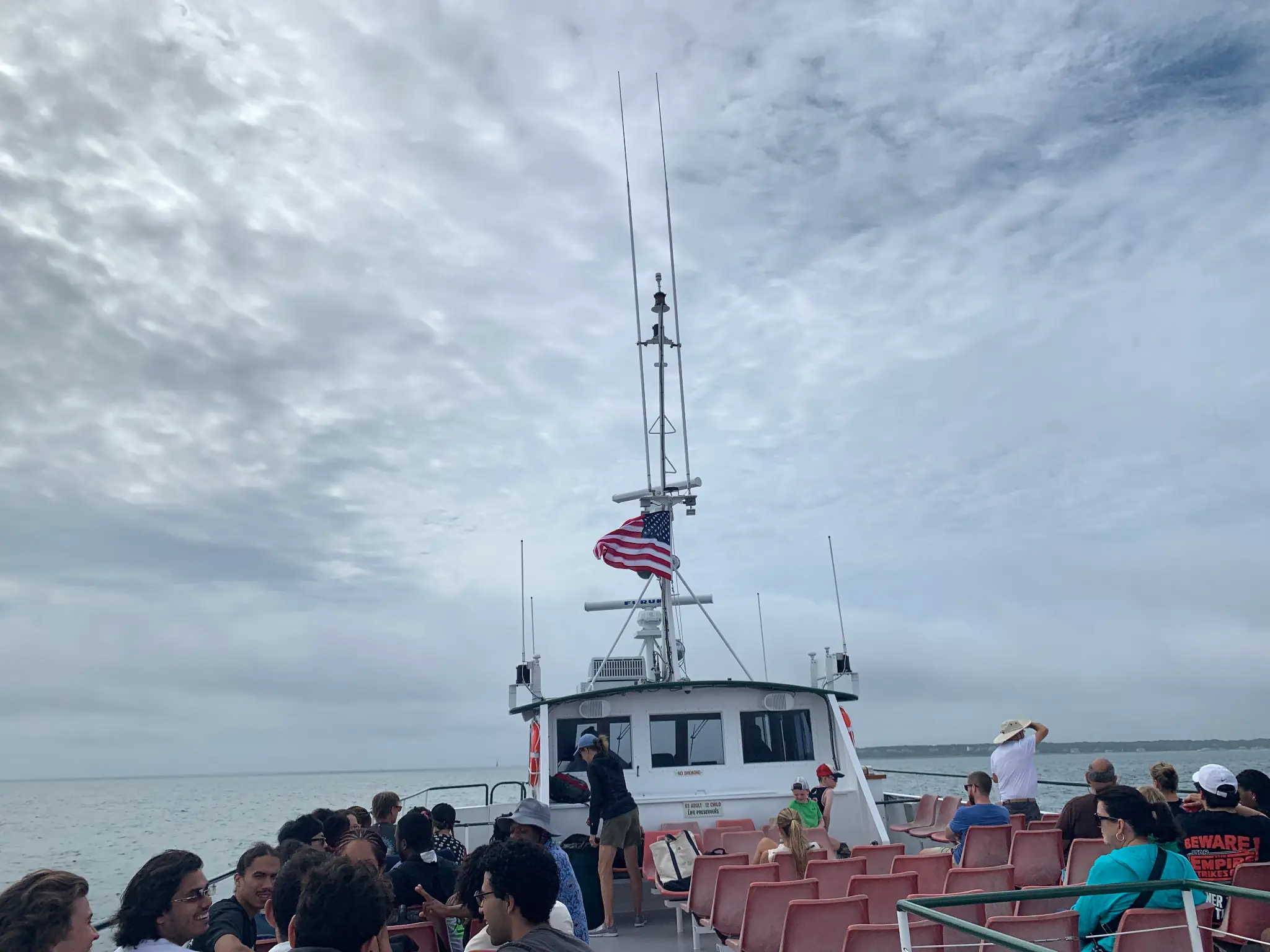 Open-air ferry crossing the water beneath an expansive cloudy sky