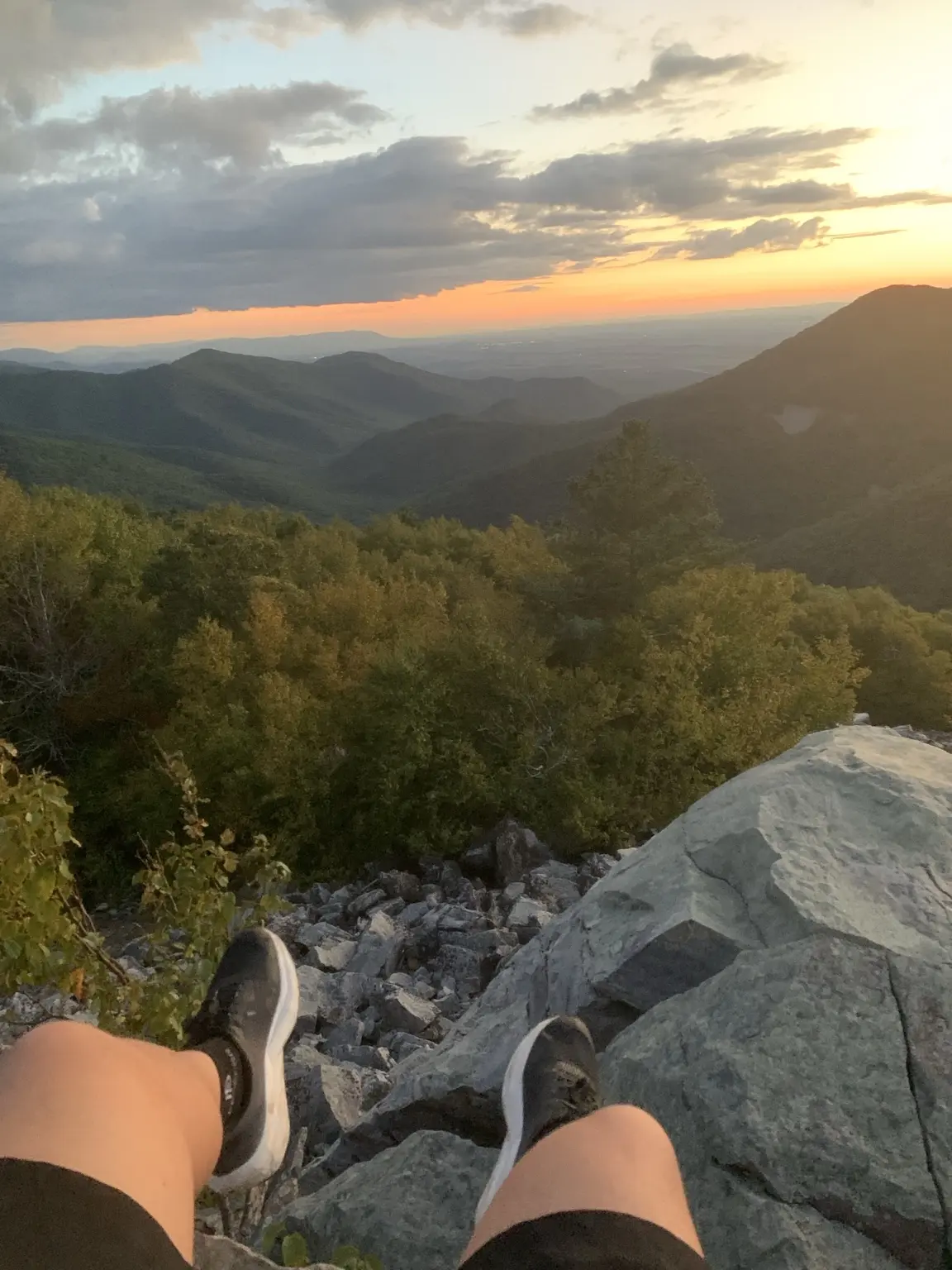 Hiking shoes overlooking a layered mountain valley at sunset