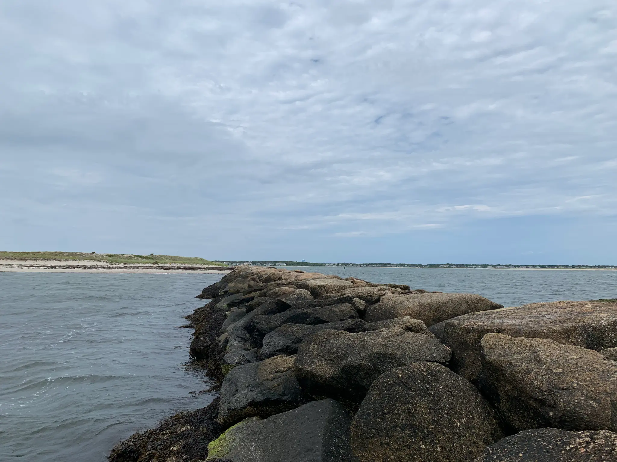 Rocky shoreline extending into the sea beneath a cloudy sky