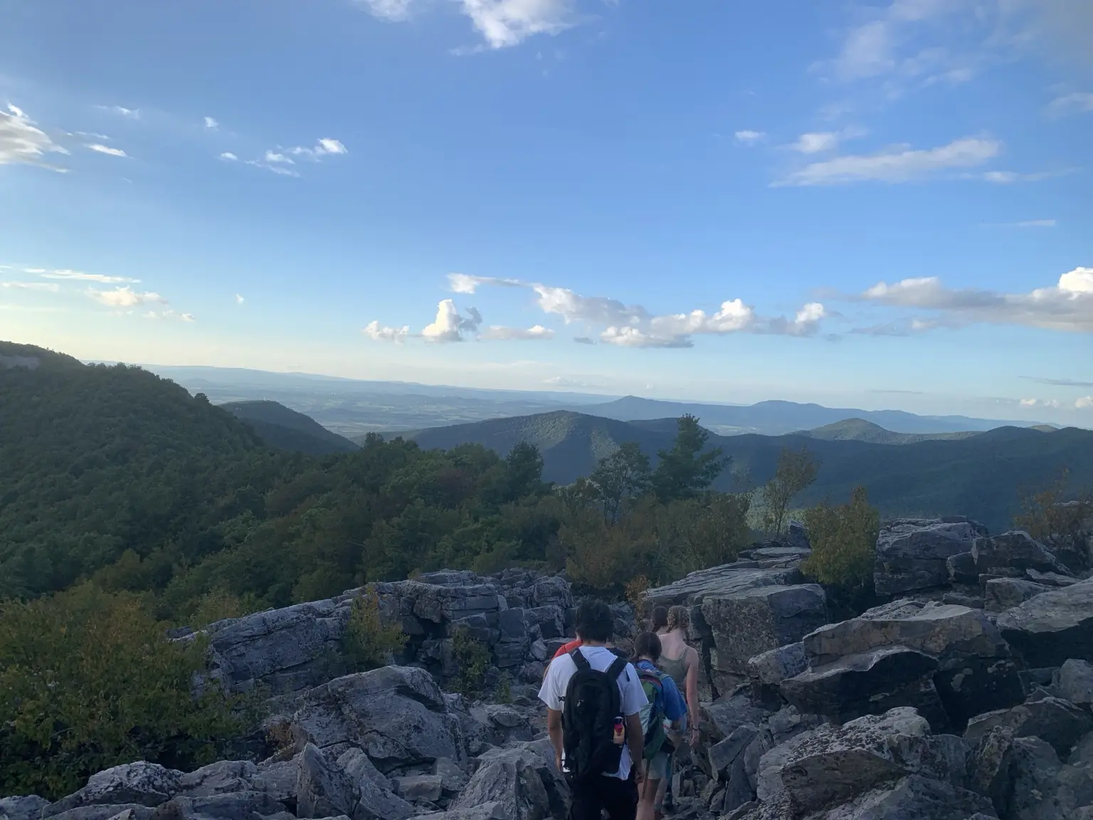Hikers descending a rocky mountain trail beneath a blue sky