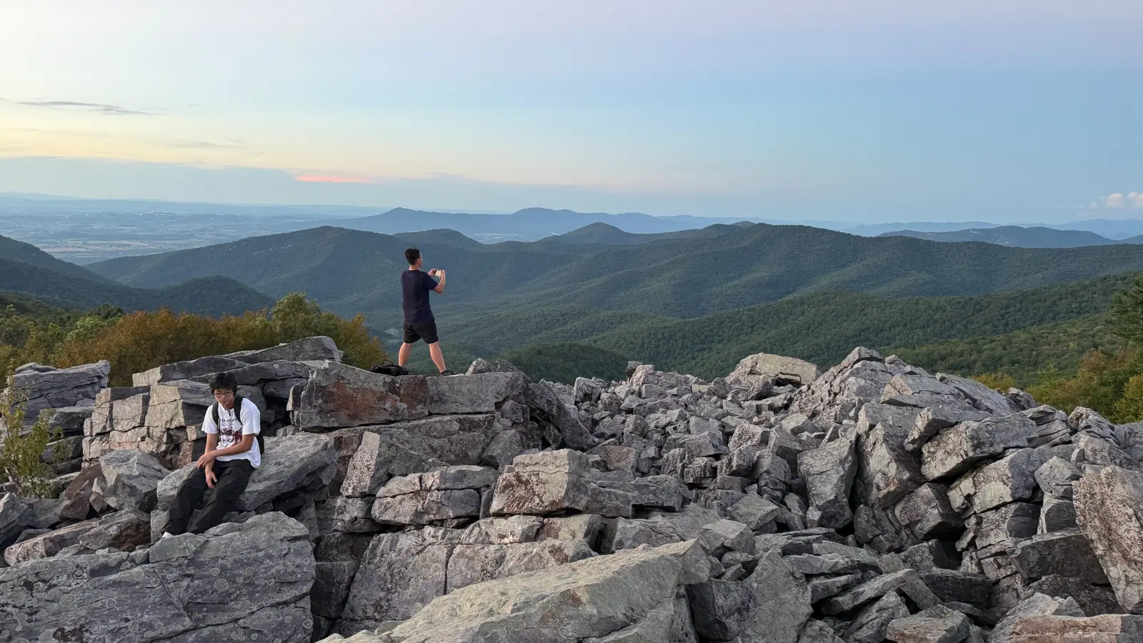 Two hikers on a rocky mountain summit overlooking the valley